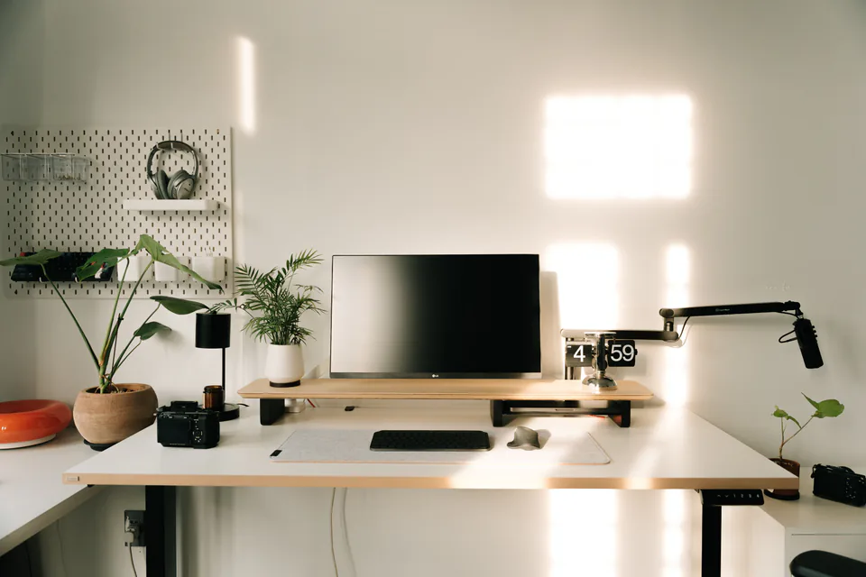 A clean, bright desk setup with a monitor and a microphone on a boom arm