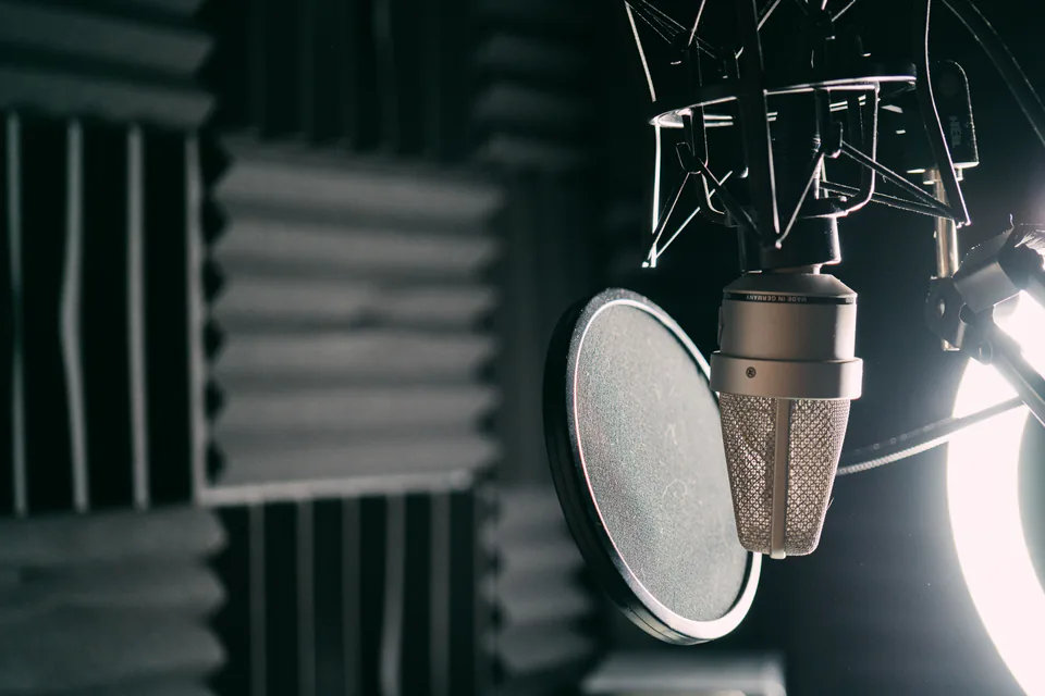 A studio microphone with a pop filter in front of acoustic foam