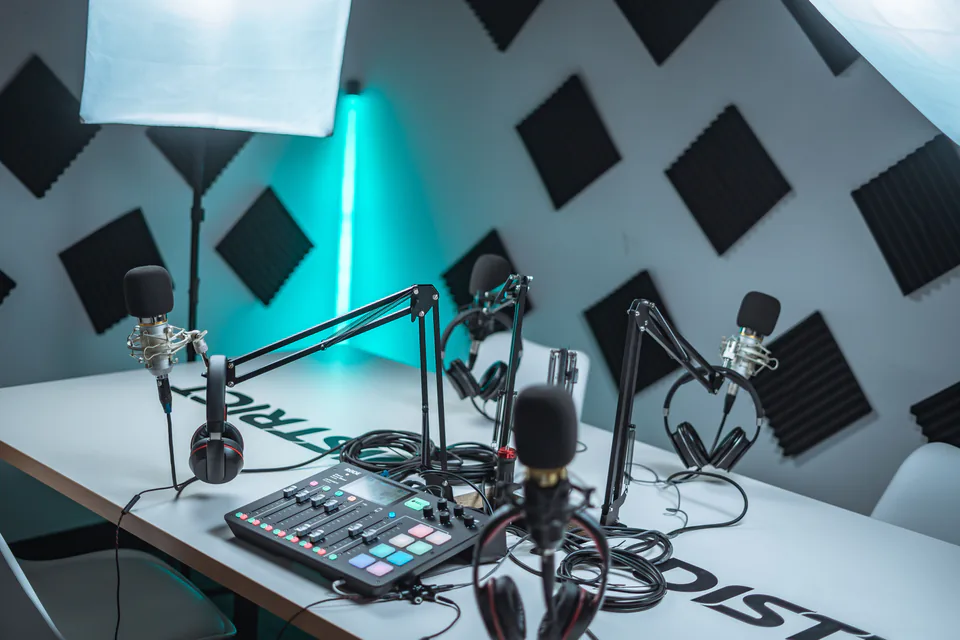 A podcast studio with acoustic panels on the wall and microphones on boom arms