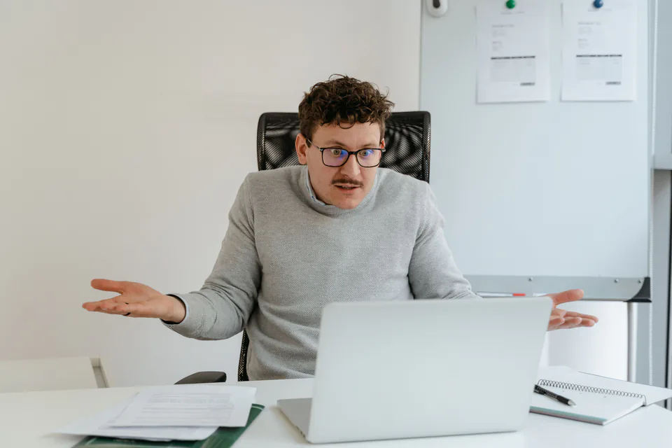 A man gesturing at his laptop during a video meeting